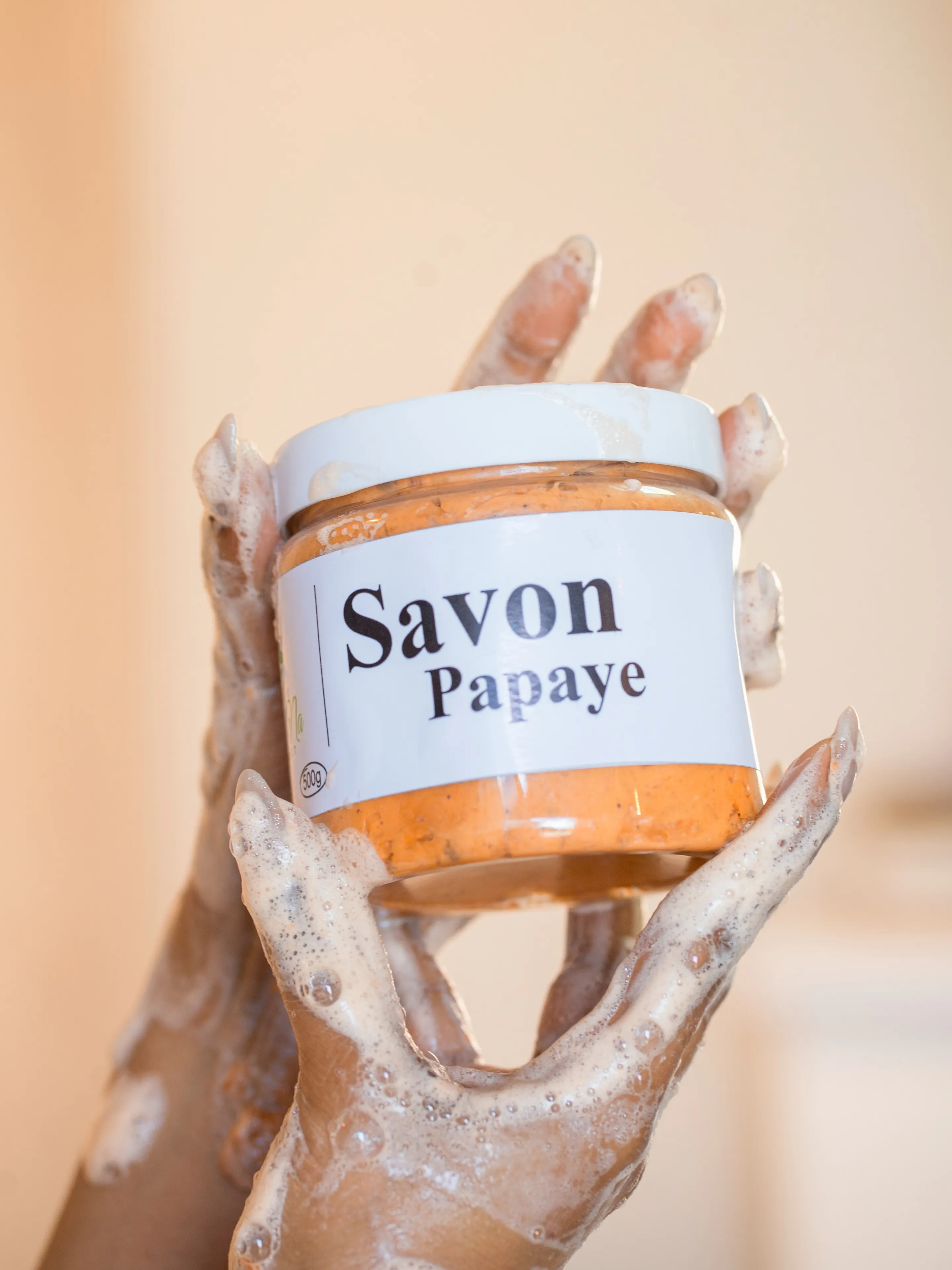 Mains couvertes de savon tenant un pot Savon Papaye
